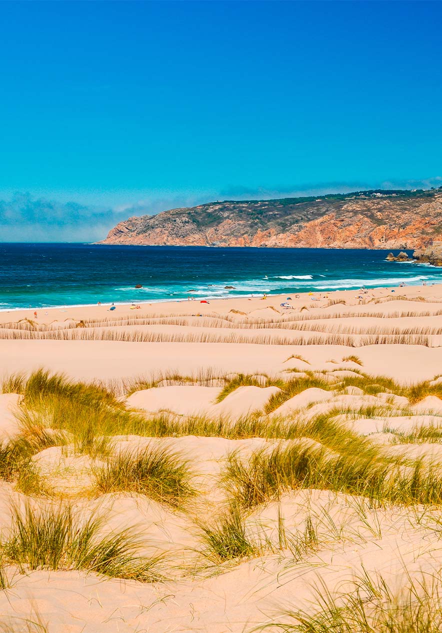 Praia do Guincho in Cascais, wo ein perfekter Strandtag mit goldenen Sand, Dünen und blauem Meer zu sehen ist