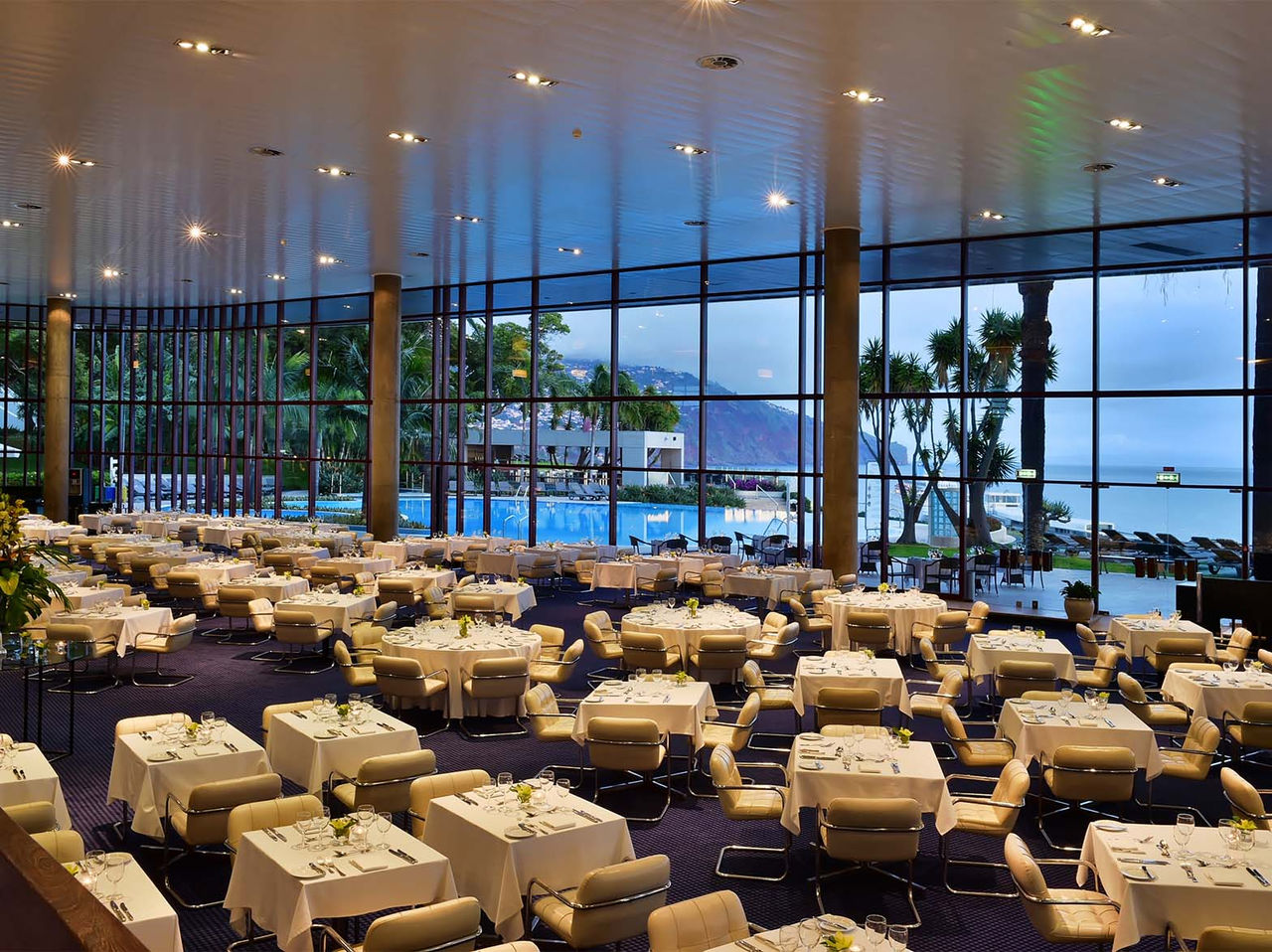 Das Restaurant Panorâmico im 5-Sterne-Hotel im Zentrum von Funchal hat mehrere Tische und gepolsterte Stühle in Beige