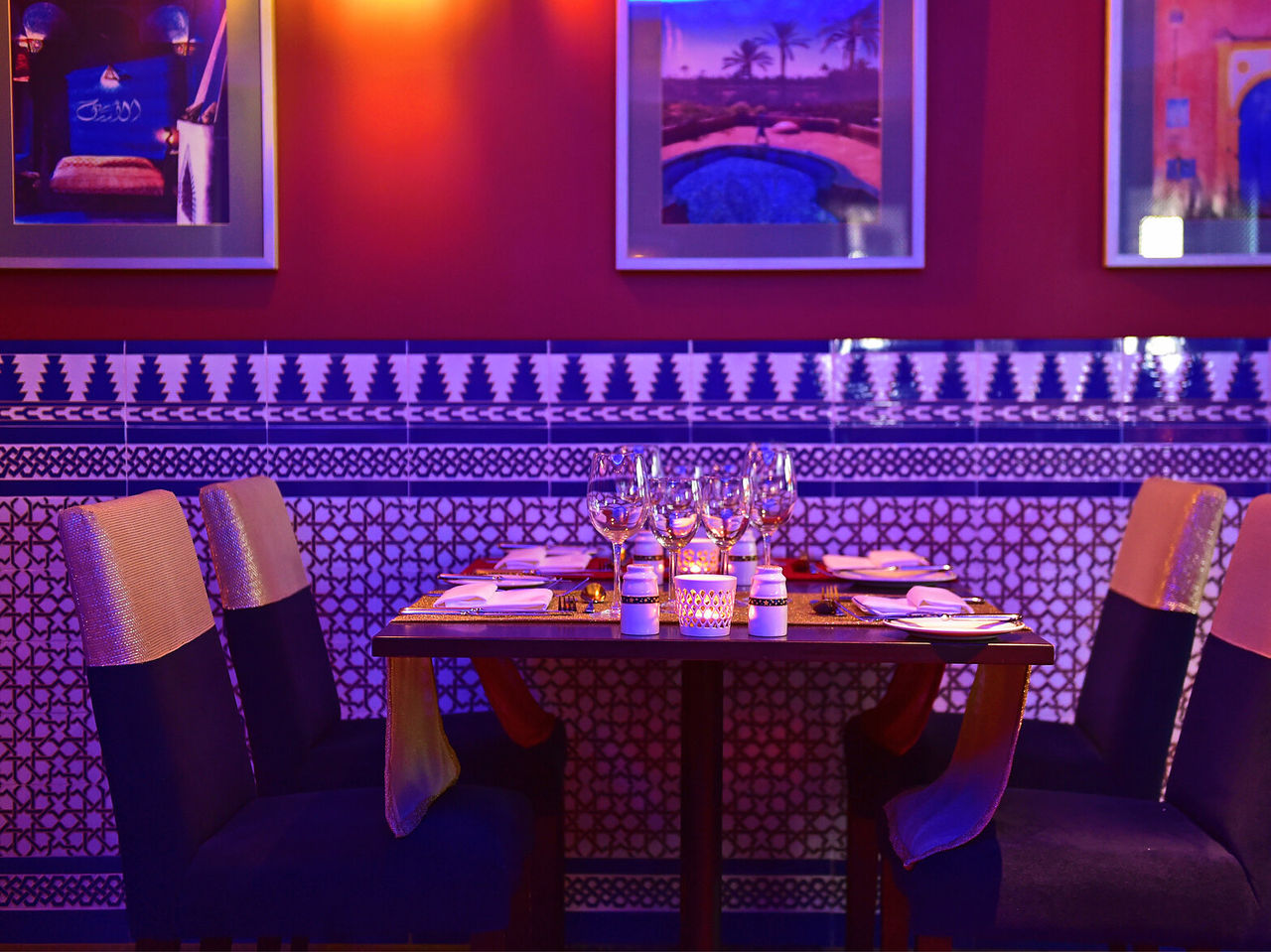 Das Restaurant Au Tagine im 5-Sterne-Hotel in Funchal, Madeira, hat einen Tisch mit vier Stühlen und Bildern an der Wand