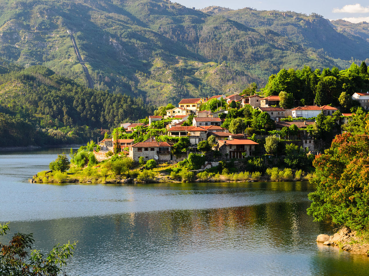 Kleines Dorf mit roten Dächern am Ufer des Douro, umgeben von einer grünen Landschaft