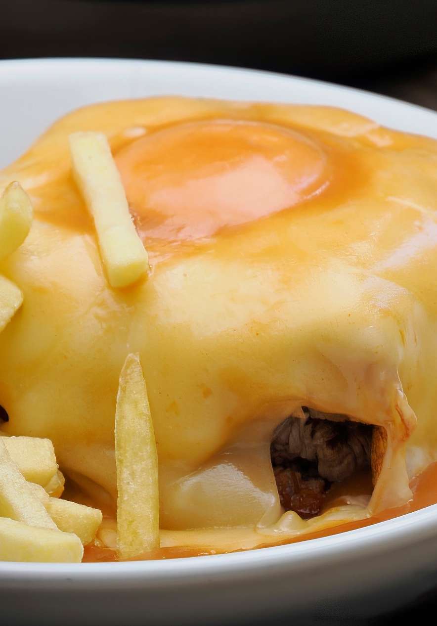 Traditionelle Francesinha, eines der berühmtesten Gerichte von Porto, mit Käse, Ei, scharfer Soße und Pommes