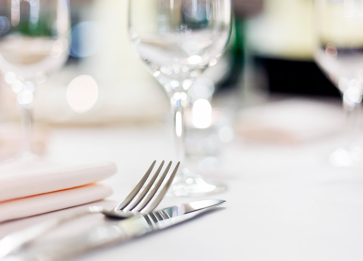 Eleganter Tisch gedeckt mit Silberbesteck, Stoffserviette und Glaswaren, in einem gut beleuchteten Ambiente