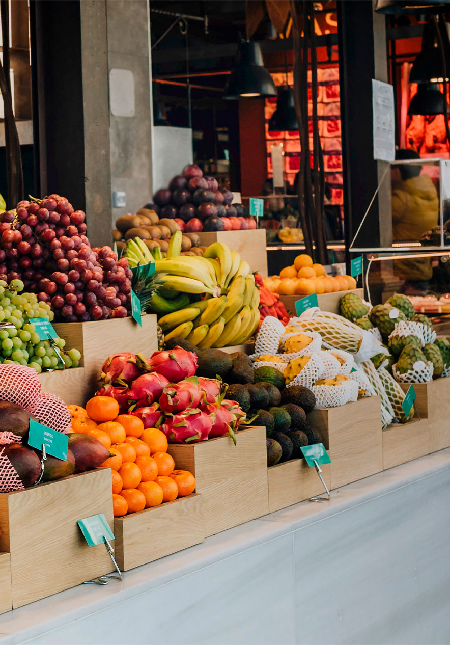 Stand mit verschiedenen Früchten auf dem Mercado de San Miguel, mit Waage und schwarzen Deckenleuchten, Glastresen