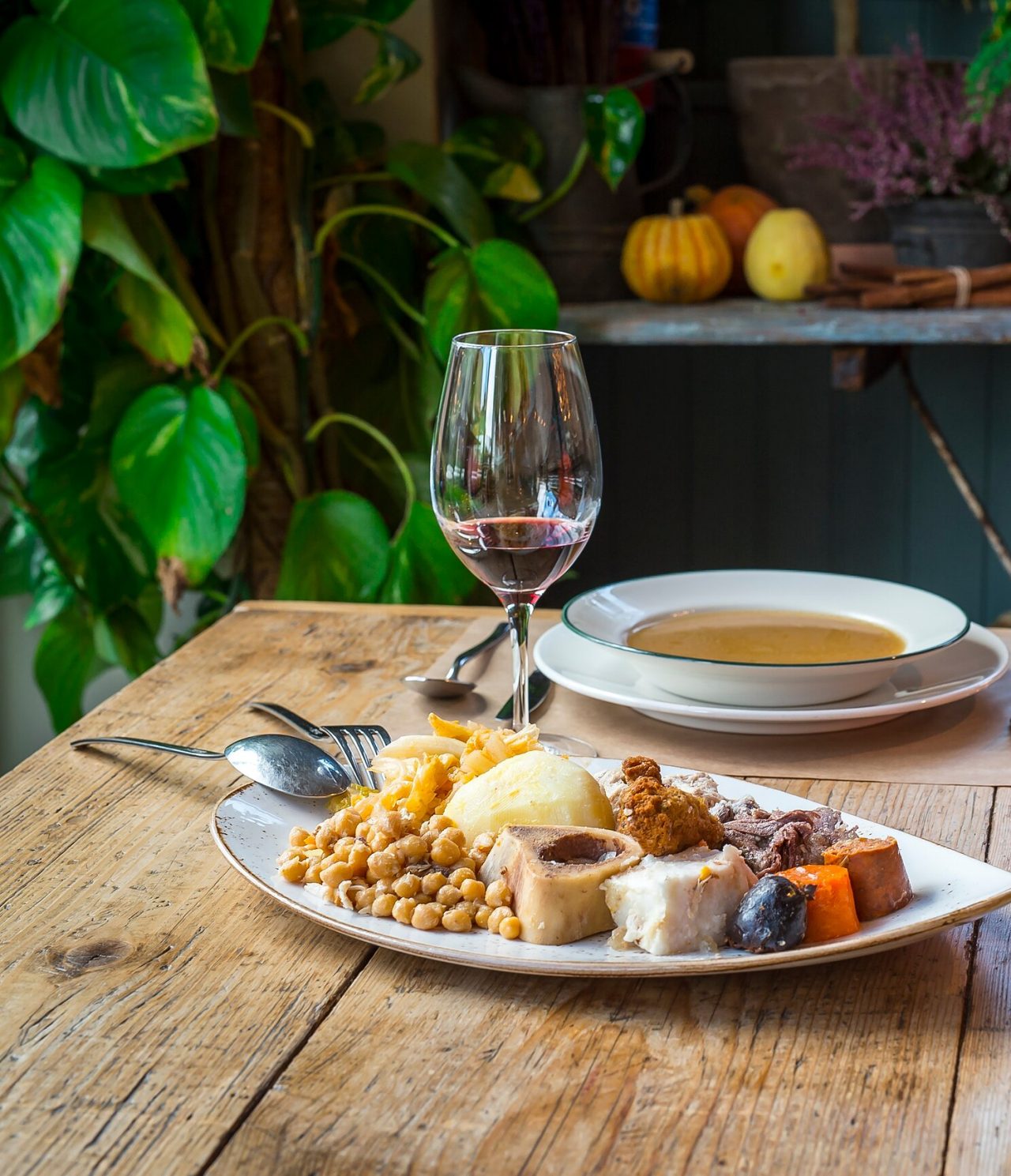 Table set with a bowl of soup, a platter of typical Madrid food, and a basket of bread