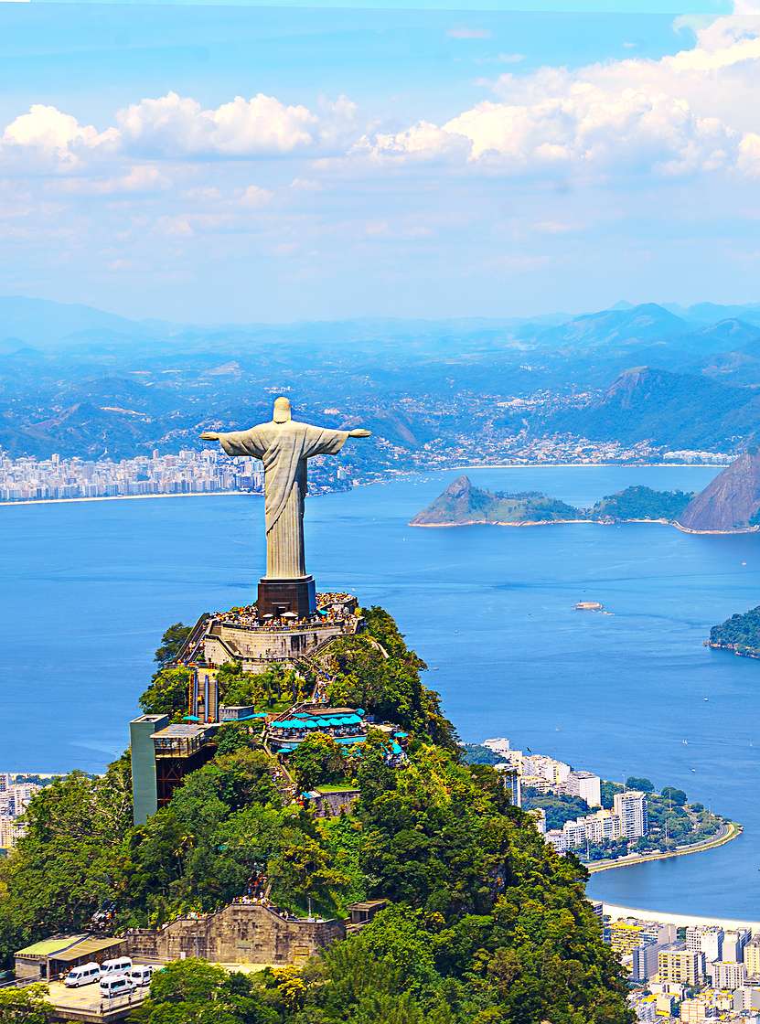 Icónica estatua del Cristo Redentor en Río de Janeiro, con la ciudad, el océano y la playa de fondo.