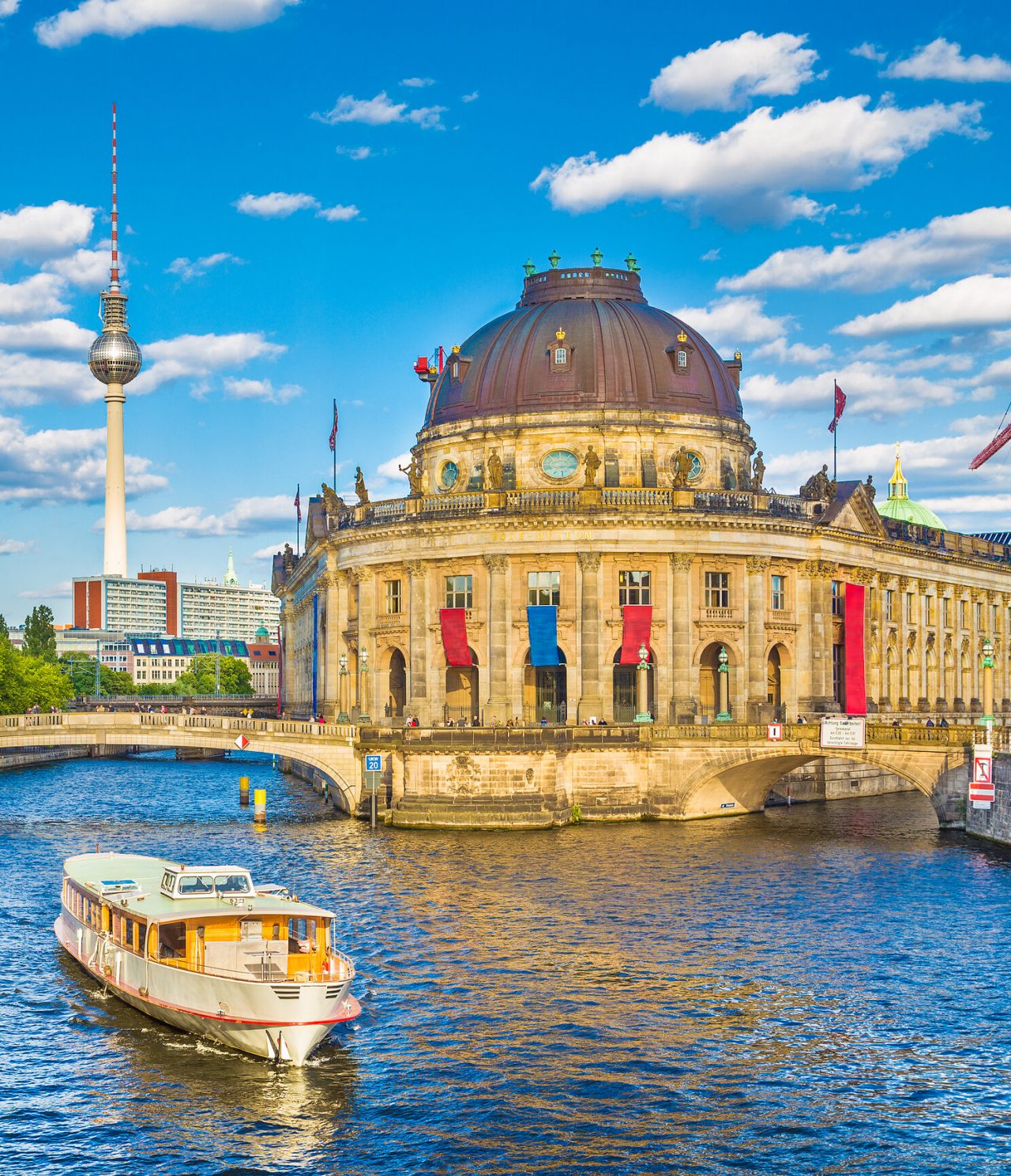 Ciudad de Berlín, con un puente peatonal sobre un canal, un barco turístico, el Museo Bode y la Torre de Televisión al fondo