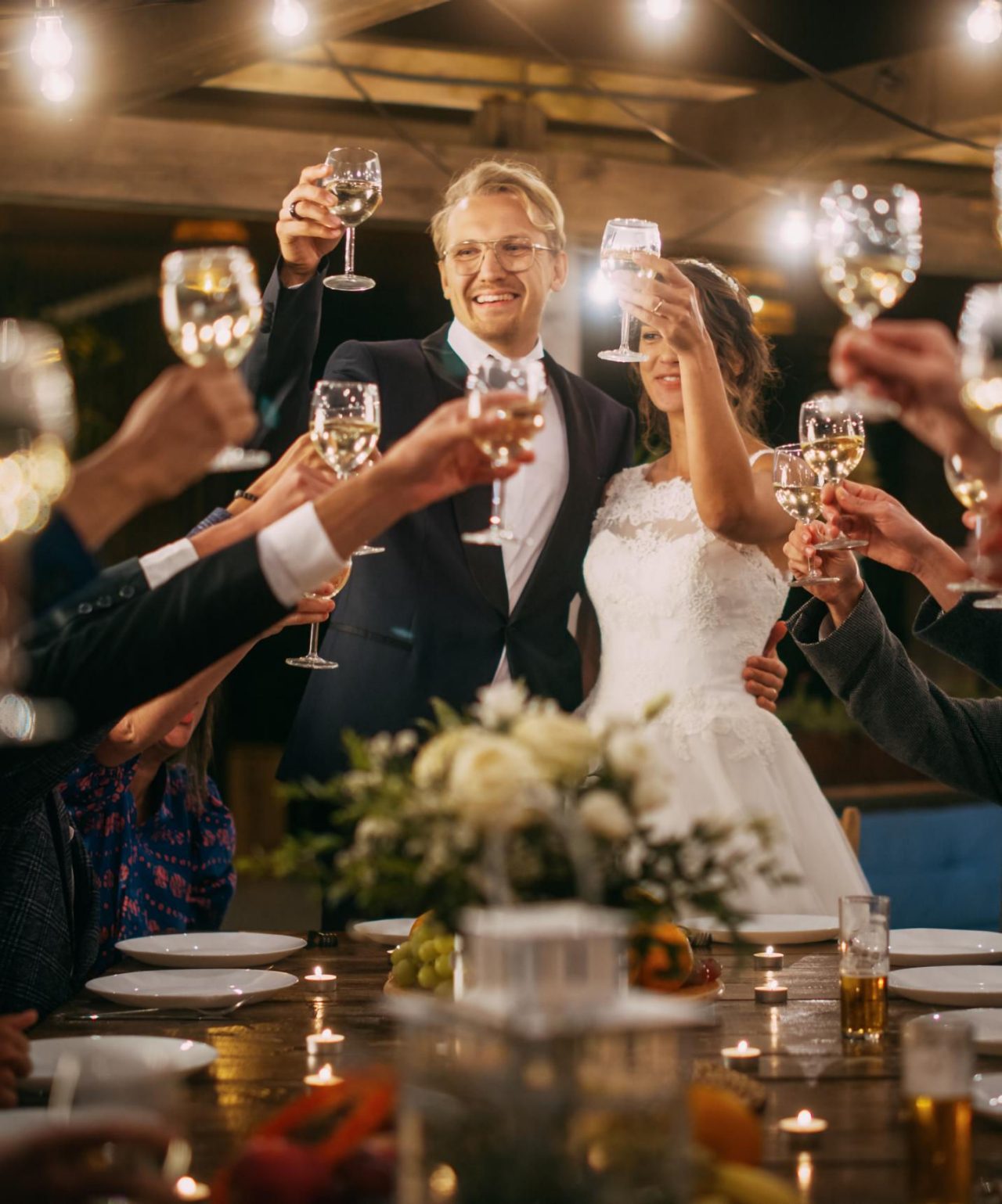 Los novios celebran su boda, brindando con sus invitados en una mesa elegante con un arreglo floral
