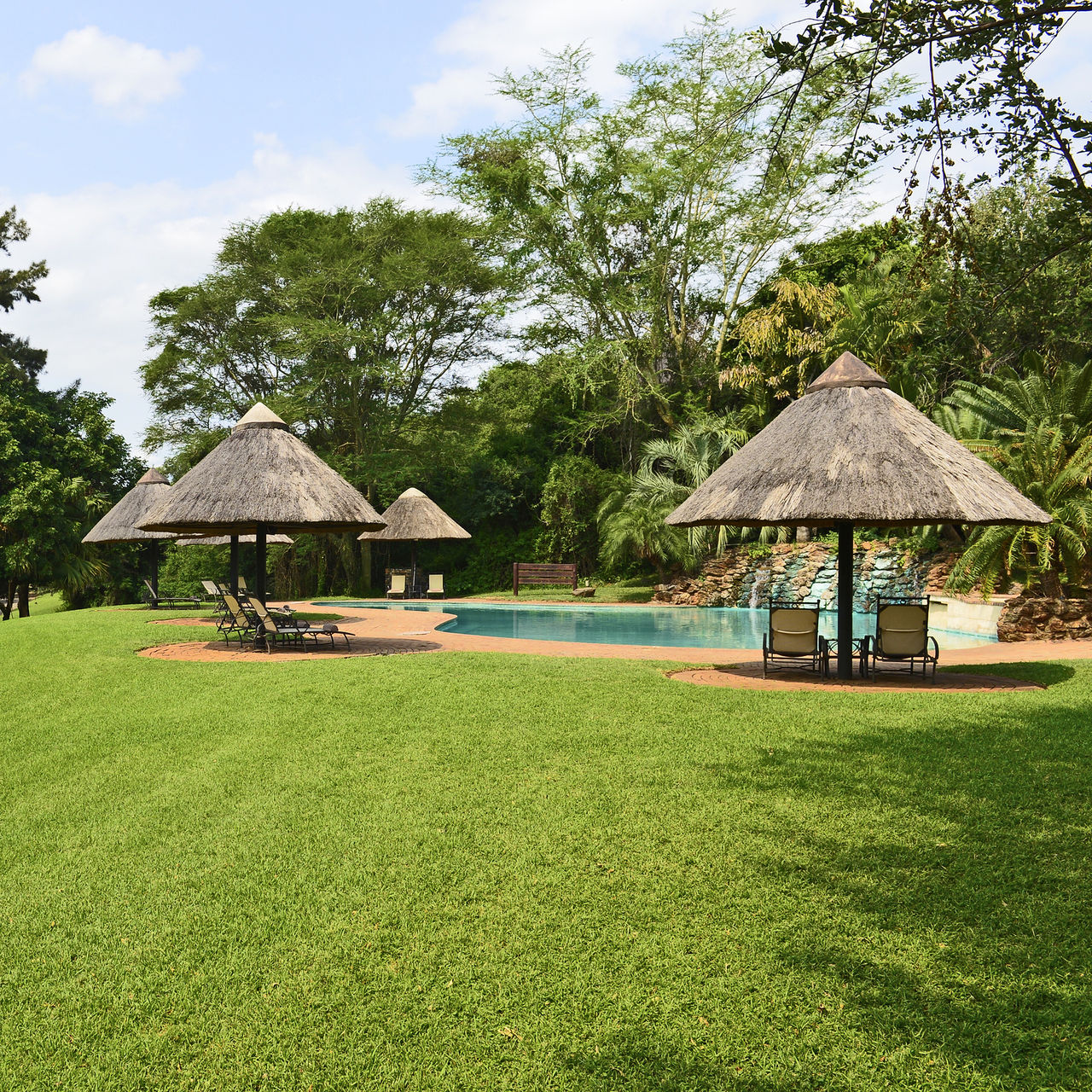 Jardin, piscine extérieure et chaises longues du Pestana Kruger Lodge, un hôtel 4 étoiles dans le parc Kruger