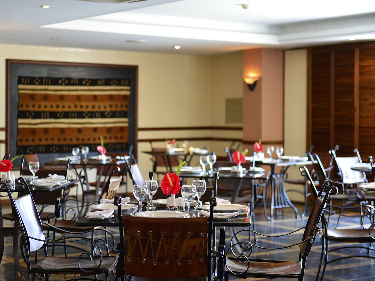Le restaurant Piazza del Campo, de l'hôtel 4 étoiles à Maputo, a tables avec fleur rouge et chaises
