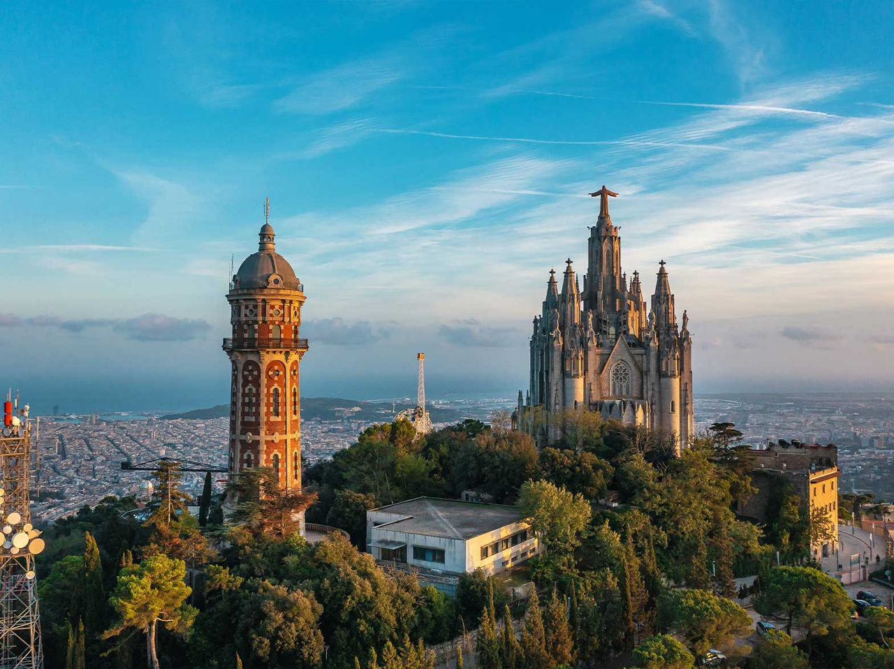 Vue du Temple du Sacré-Cœur de Jésus sur le Tibidabo, entouré de végétation avec la ville de Barcelone en arrière-plan