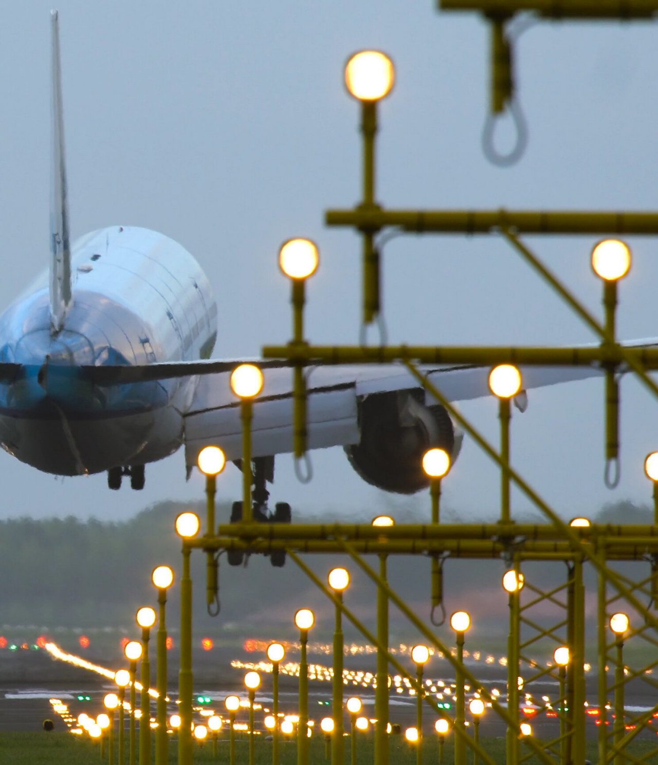 Vue d'un grand avion commercial atterrissant sur une piste éclairée avec plusieurs lumières à un aéroport