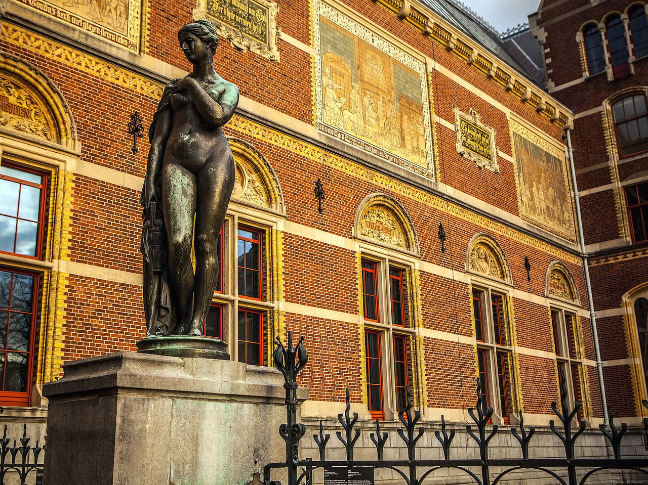 Statue d'une femme nue au Rijksmuseum, devant un bâtiment historique à Amsterdam, Pays-Bas