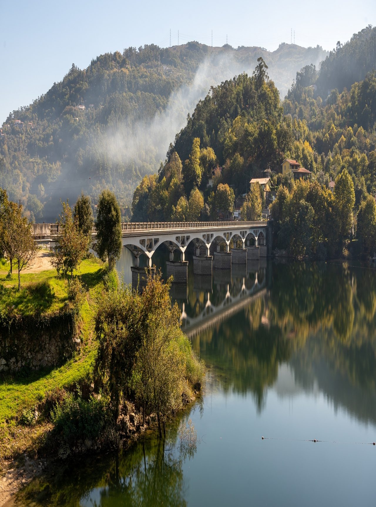 Paysage du nord du Portugal avec un pont de pierre sur une rivière, entouré de collines verdoyantes