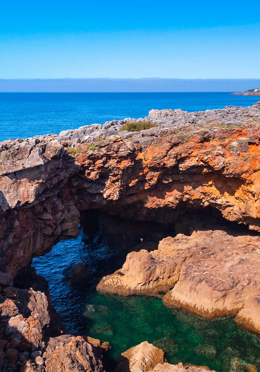 La mer bleue rencontre des rochers imposants, créant un contraste entre la sérénité de l'eau et la robustesse des roches
