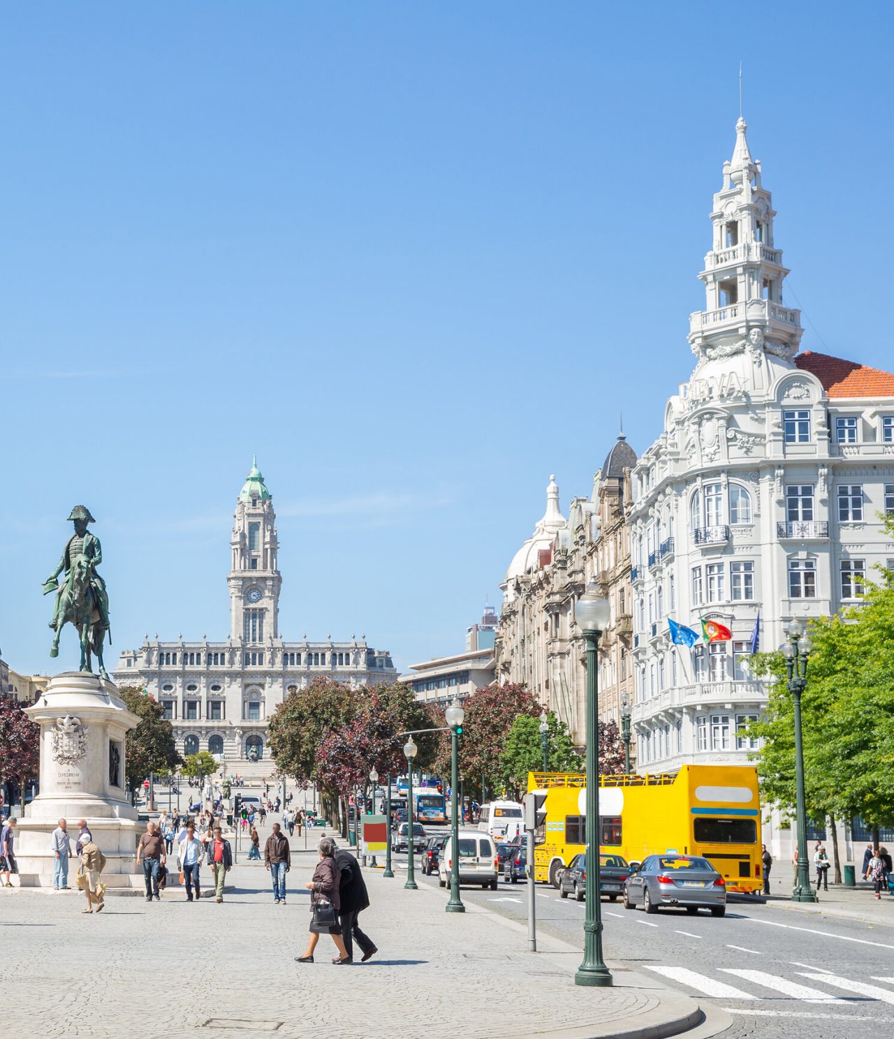 Animation de l'Avenida dos Aliados à Porto, avec des gens qui se promènent, des voitures dans la circulation et des bâtiments