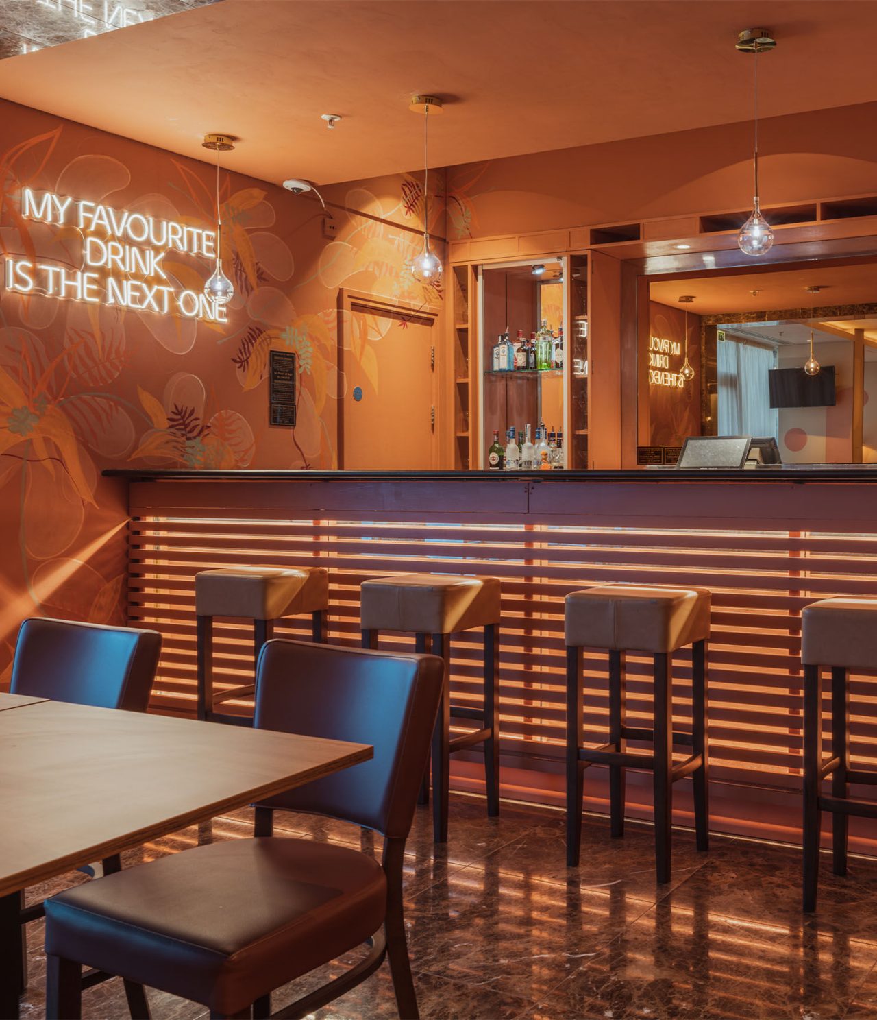Le bar The Bridge de l’hôtel 4 étoiles à Londres a un comptoir avec des bancs hauts et une lumière LED au mur