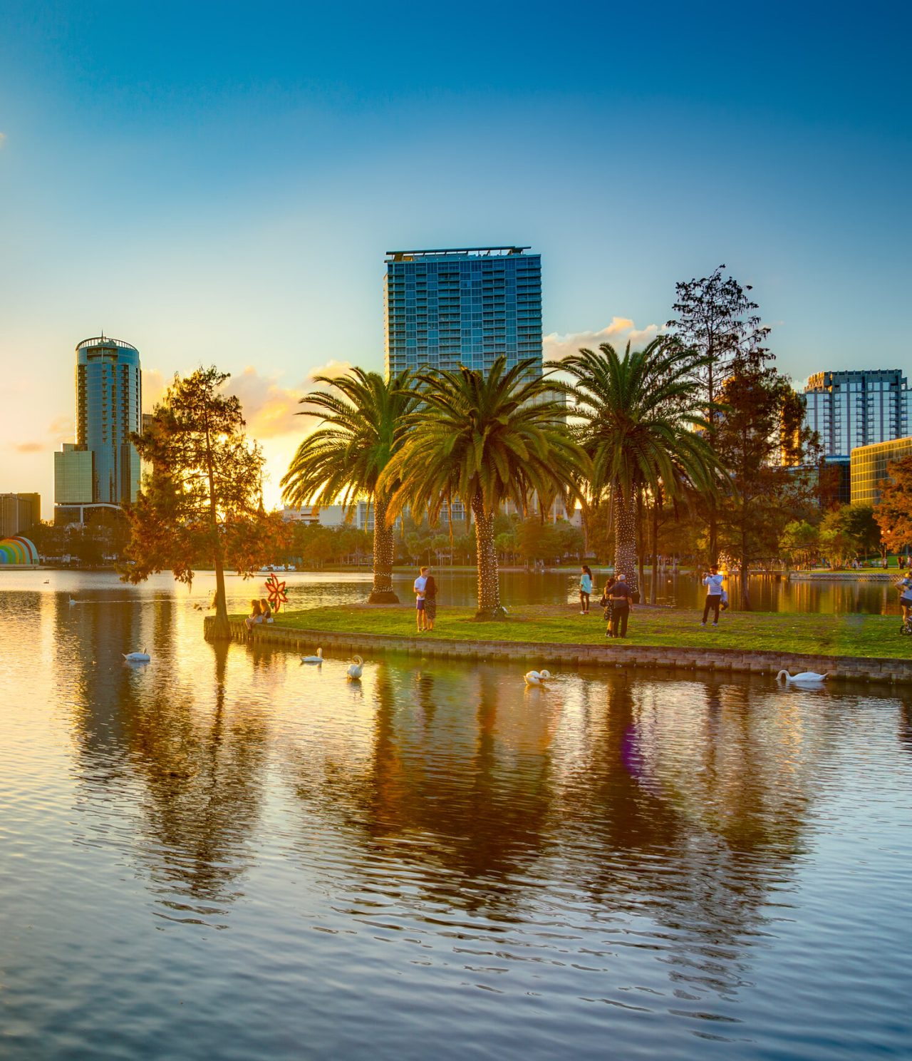 Vue panoramique d'Orlando, avec un lac serein où le coucher du soleil se reflète sur les eaux calmes du lac