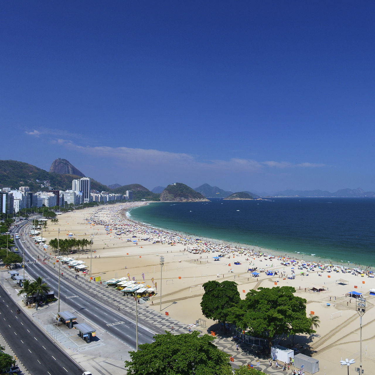 Plage de Copacabana à Rio de Janeiro, plage animée avec sable doré, mer bleue et montagnes en arrière-plan