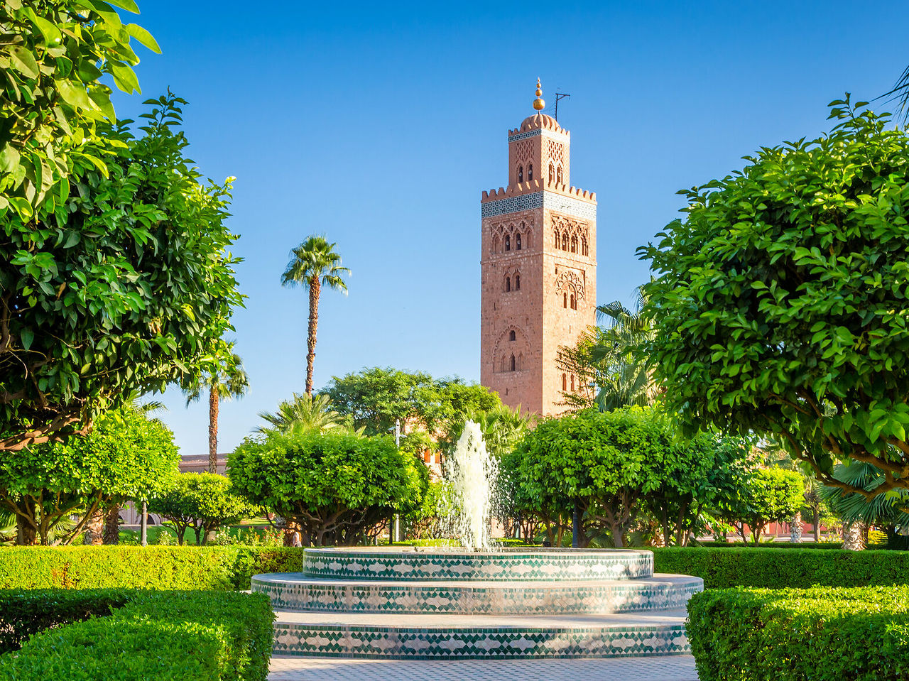 Uitzicht op de Koutoubia-moskee, historisch monument, omgeven door bomen en een typische Marokkaanse fontein