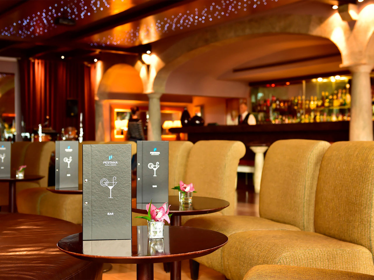 De bar Taverna, van het 5-sterrenhotel op Madeira, heeft banken met tafels en menu's, en een vaas met bloemen