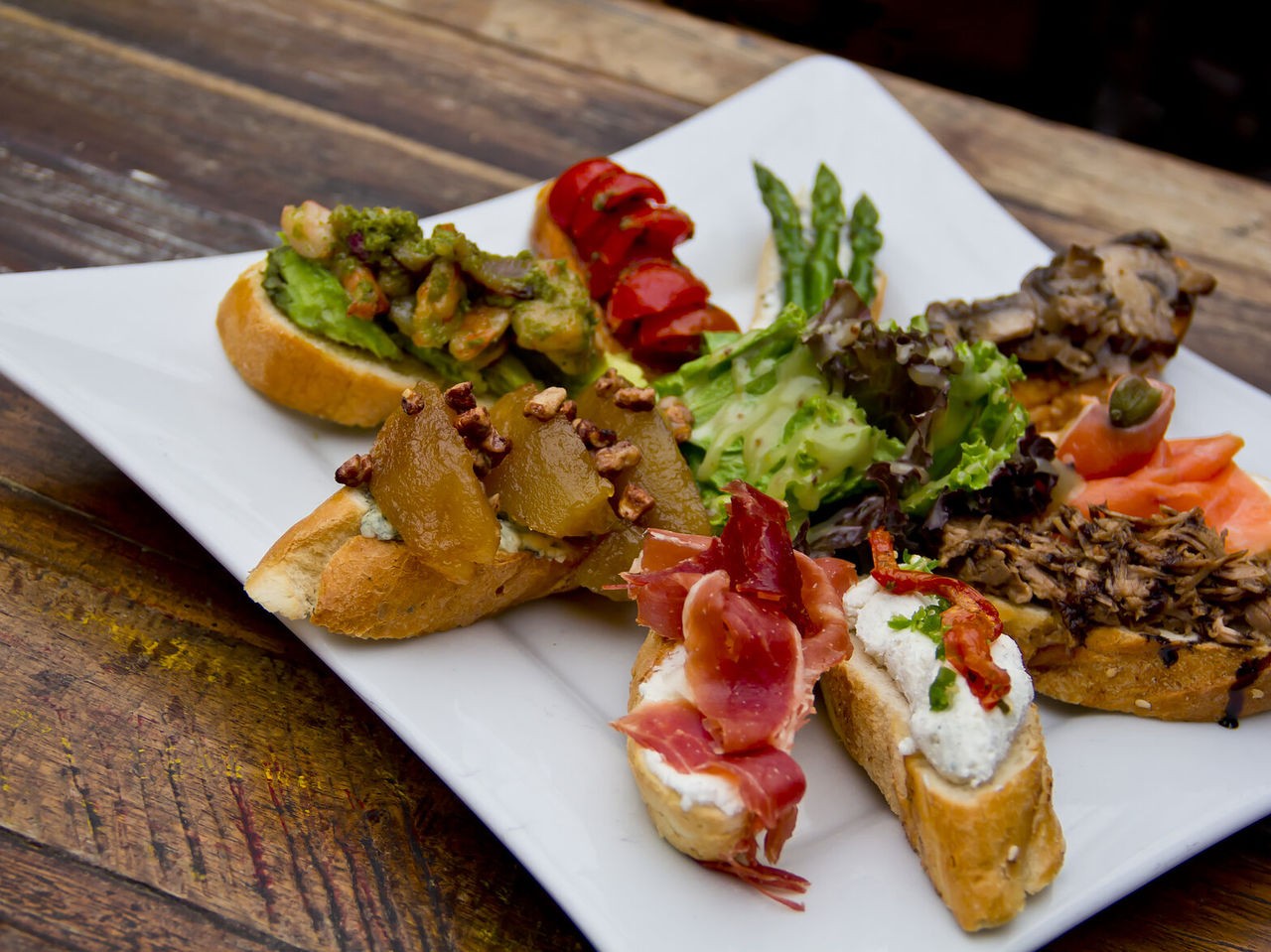 Schotel met bocadillos, typische Spaanse tapas, met verschillende toppings op brood, van ham tot kaas en tomaat