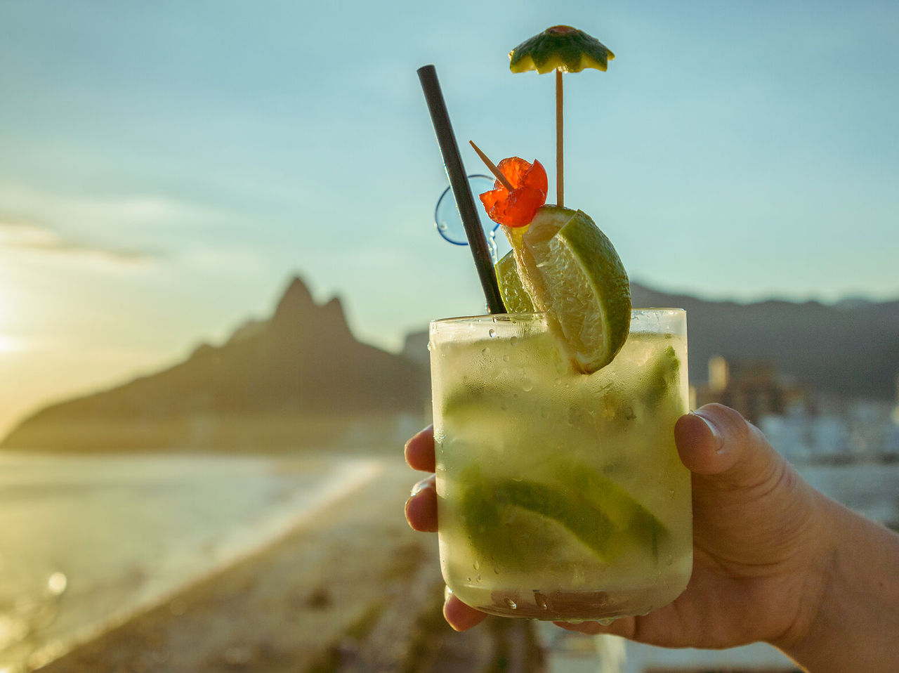 Typische caipirinha uit Rio de Janeiro met het strand van Ipanema en de Dois Irmãos heuvel op de achtergrond