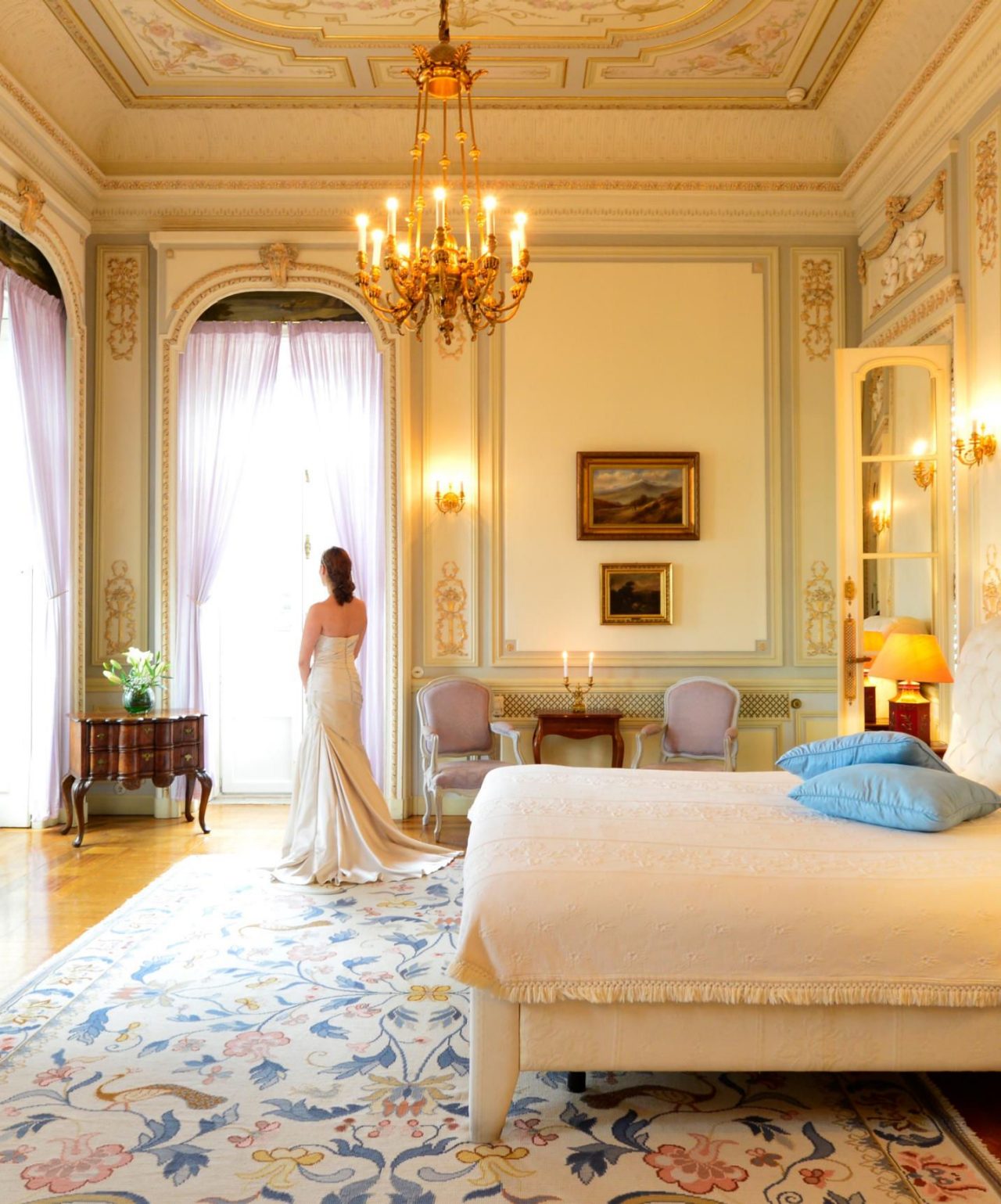 Bruid bereidt zich voor op haar huwelijk in een elegante hotelkamer, met muren versierd met gouden details en een kristallen kroonluchter