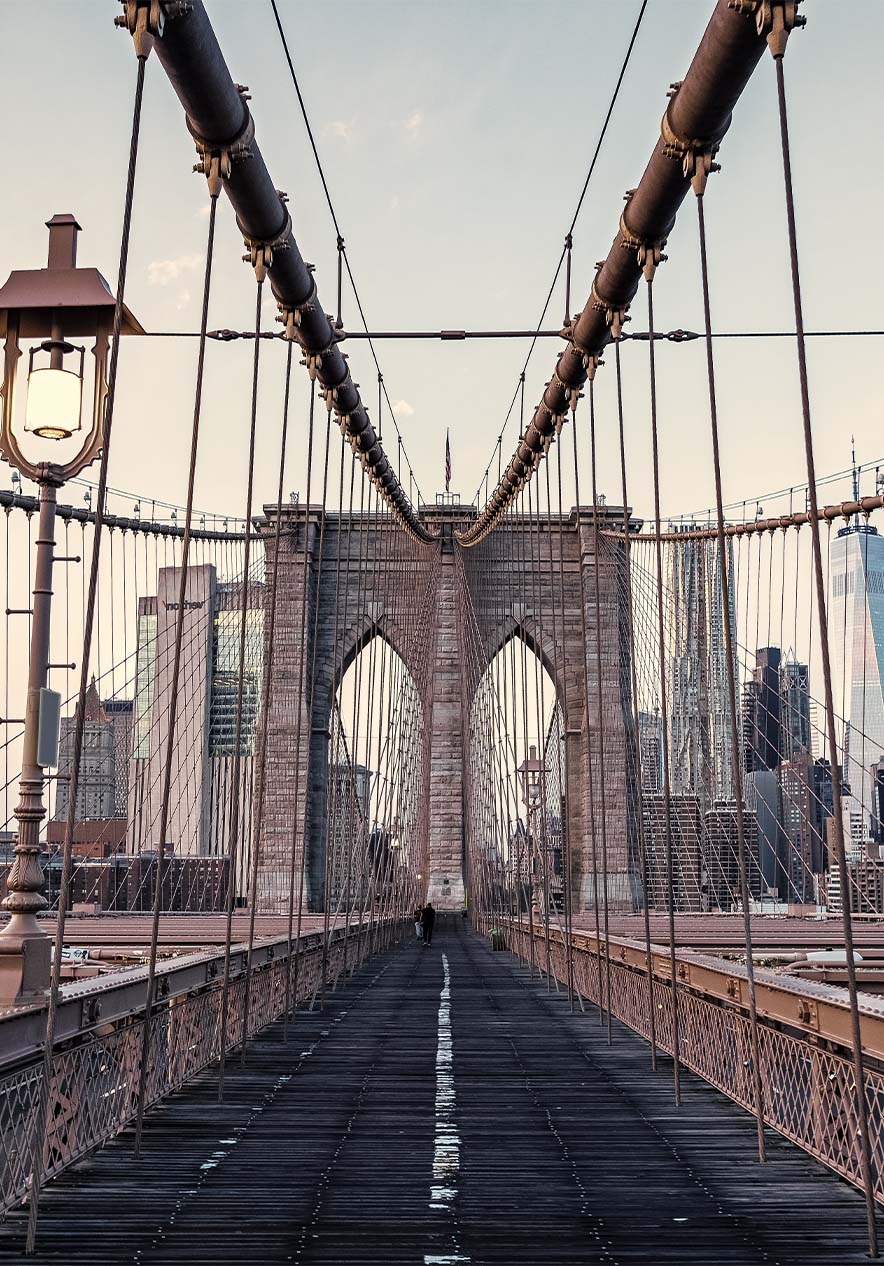 Vista panorâmica da ponte do Brooklyn, com seus cabos de aço e estrutura de ferro, sob um céu azul claro