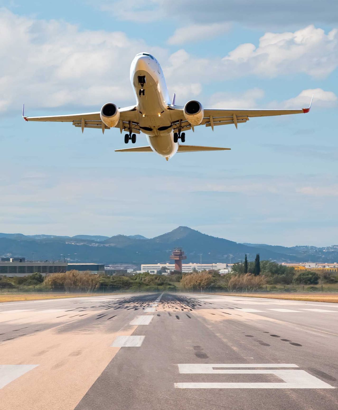 Avião comercial de grande porte, a descolar de uma pista de aeroporto, em Barcelona, com a torre de controlo no fundo