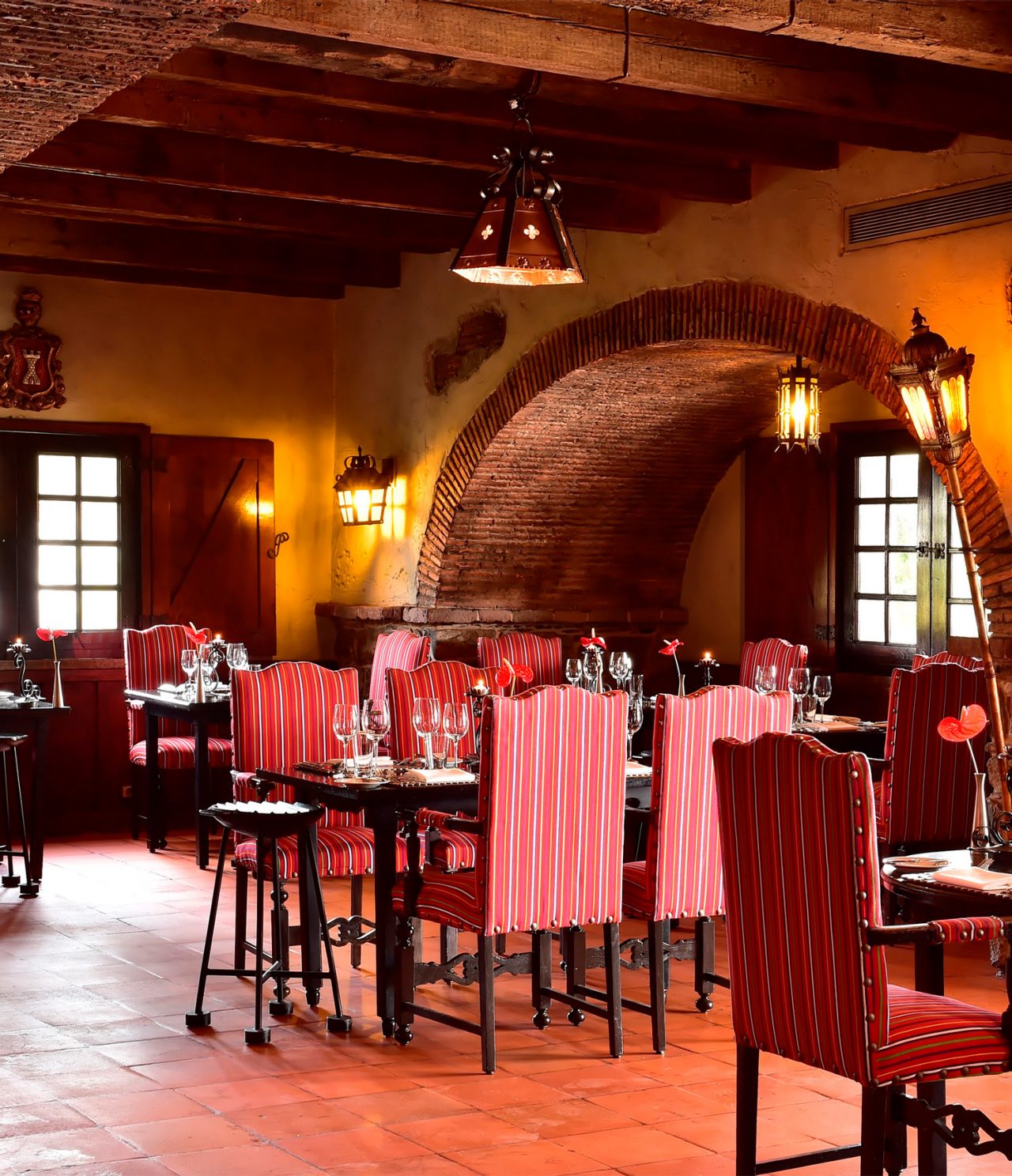 O restaurante Taverna Grill, do Hotel 5 Estrelas na Madeira, tem um espaço amplo com cadeira vermelhas, mesas e candeeiros