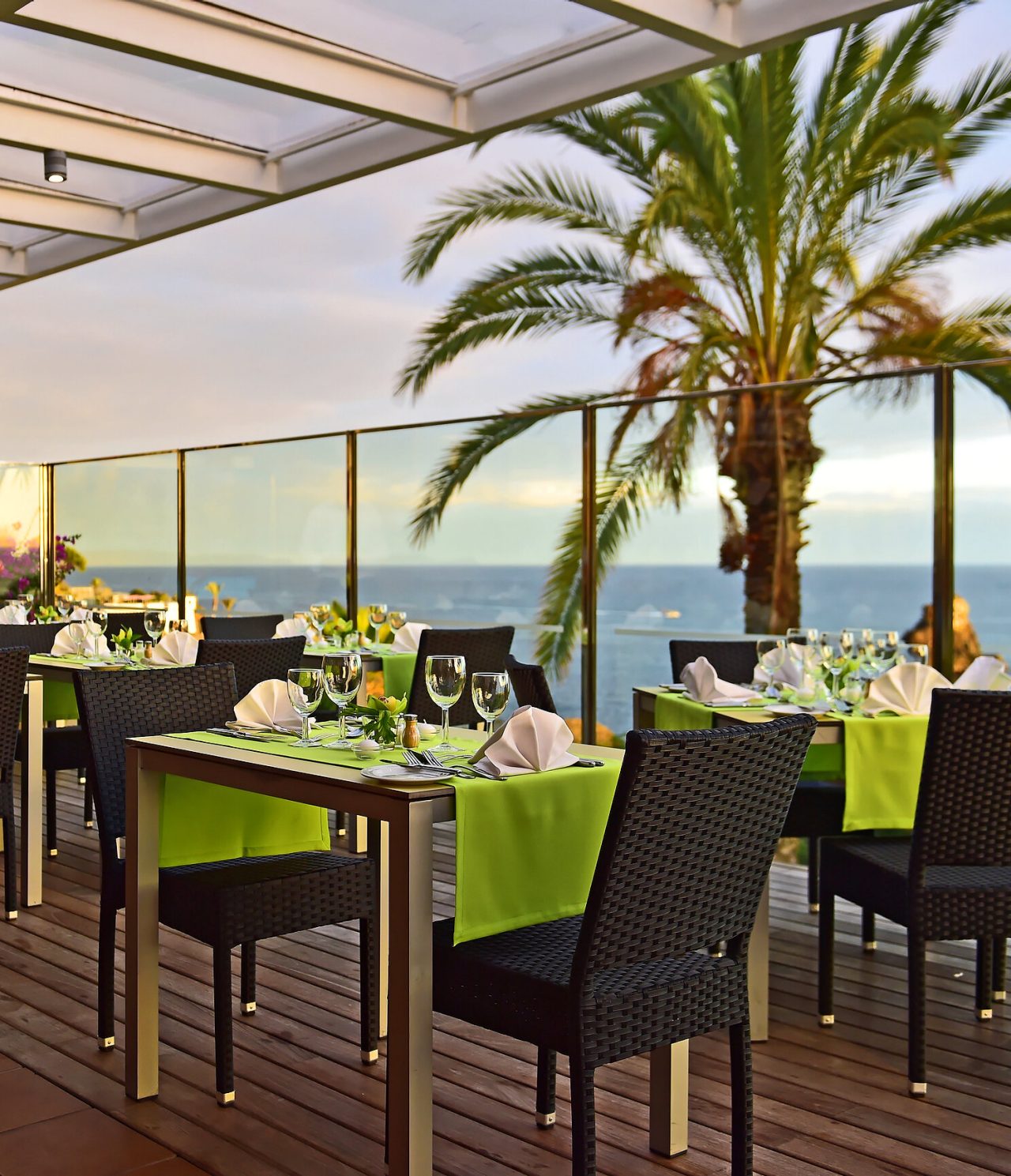 O restaurante The Deck, do Hotel 4 Estrelas Junto ao Mar no Funchal, tem várias mesas com toalha verde com vista para o mar