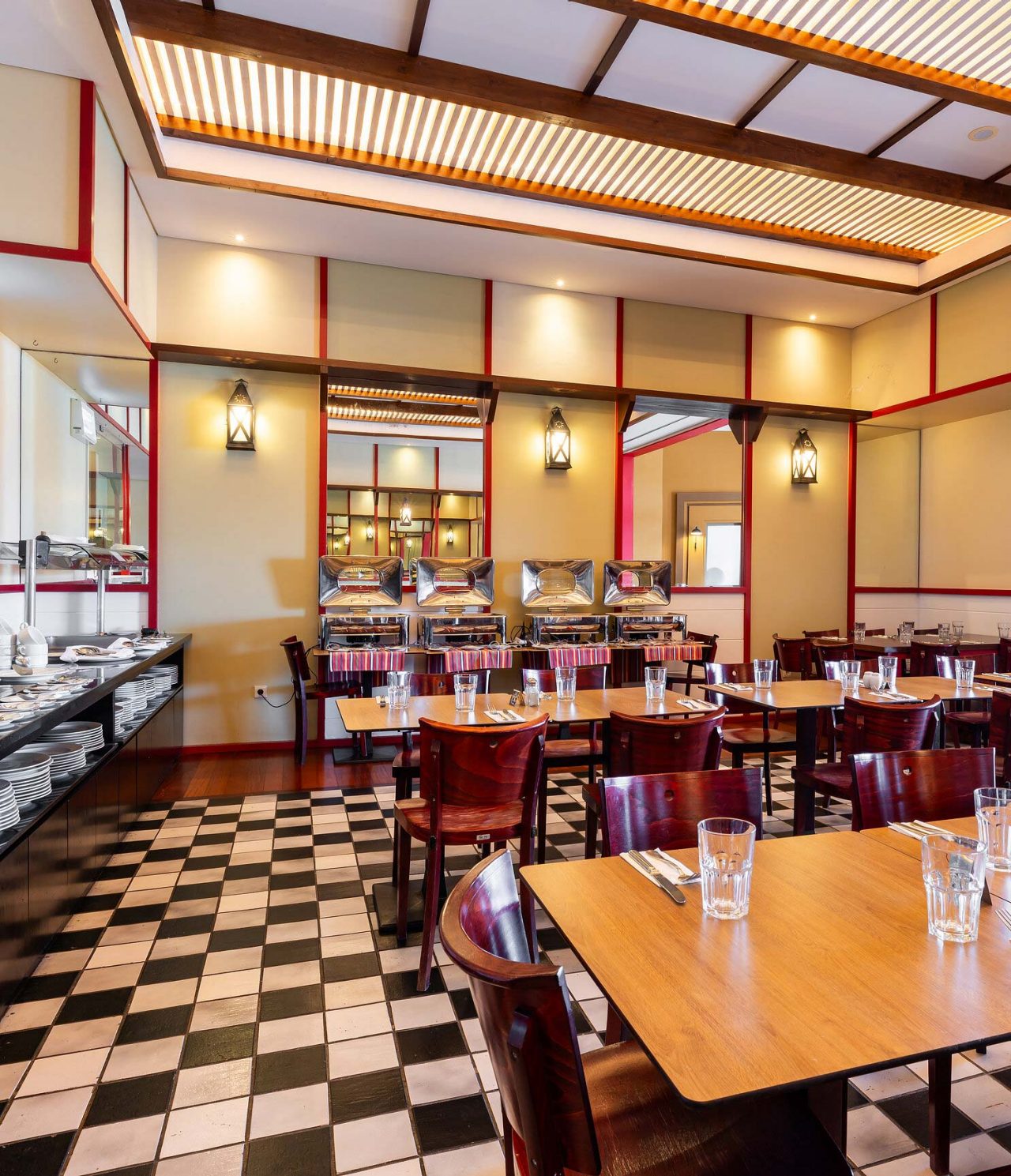 O restaurante Luigi, do Resort de 5 Estrelas no Porto Santo tem um chão com azulejos brancos e pretos e cadeiras escuras