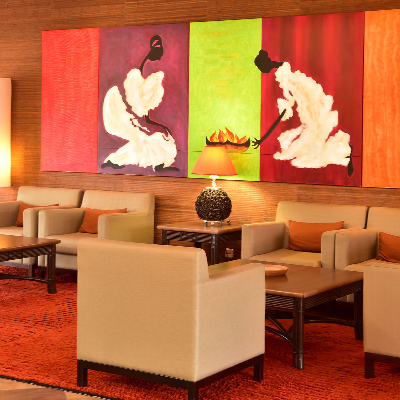 Reception lounge with three armchairs, a bedside table with a lamp, and a painted picture hanging on the wall