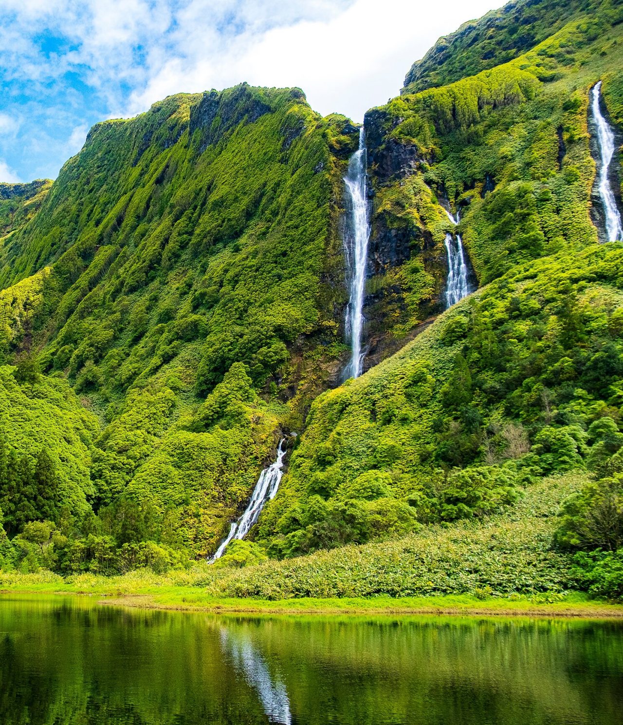Stunning waterfall surrounded by green vegetation-covered mountains on Flores Island, Azores