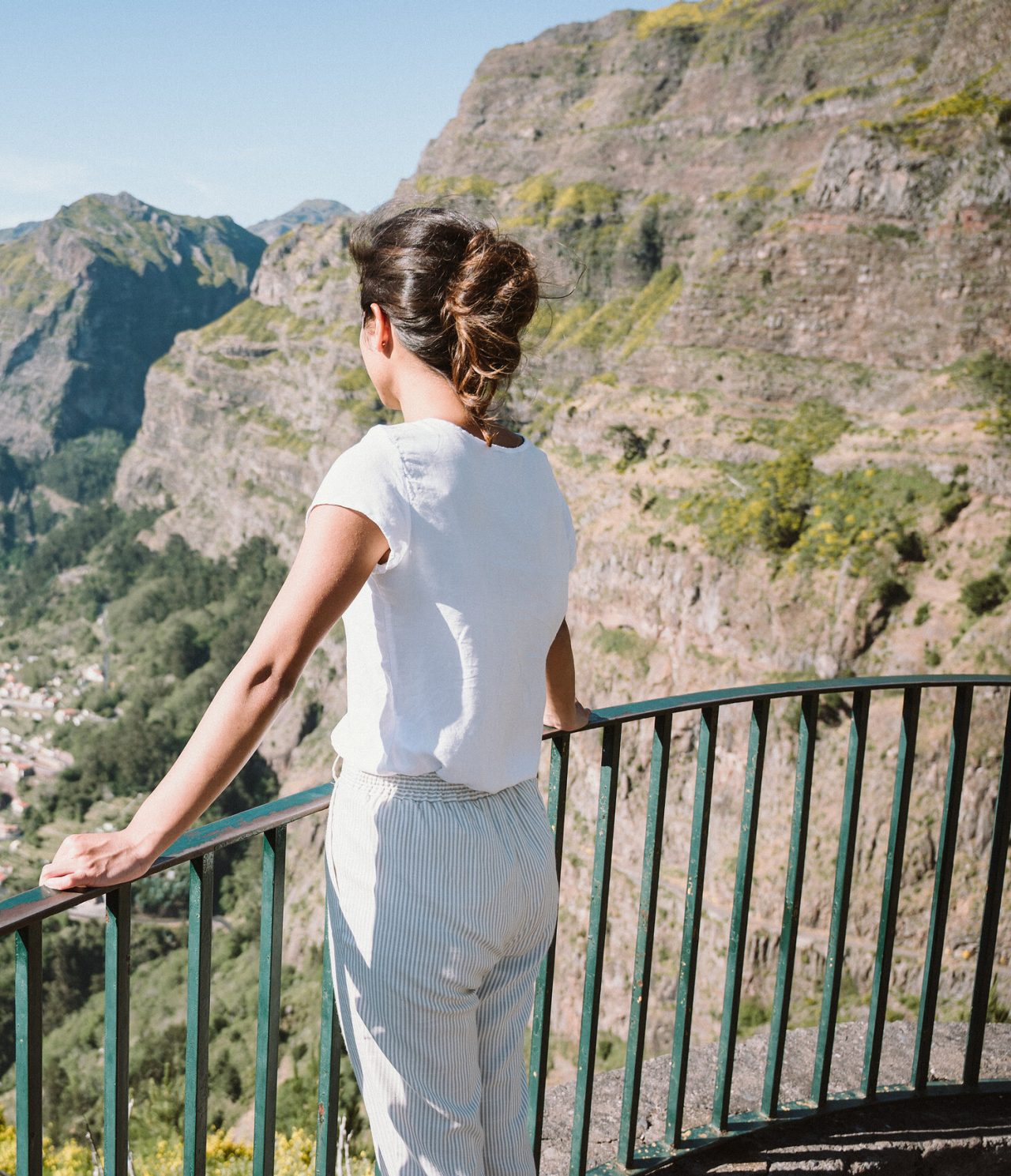 Woman enjoying the view from Curral das Freiras viewpoint, overlooking a valley amidst lush vegetation