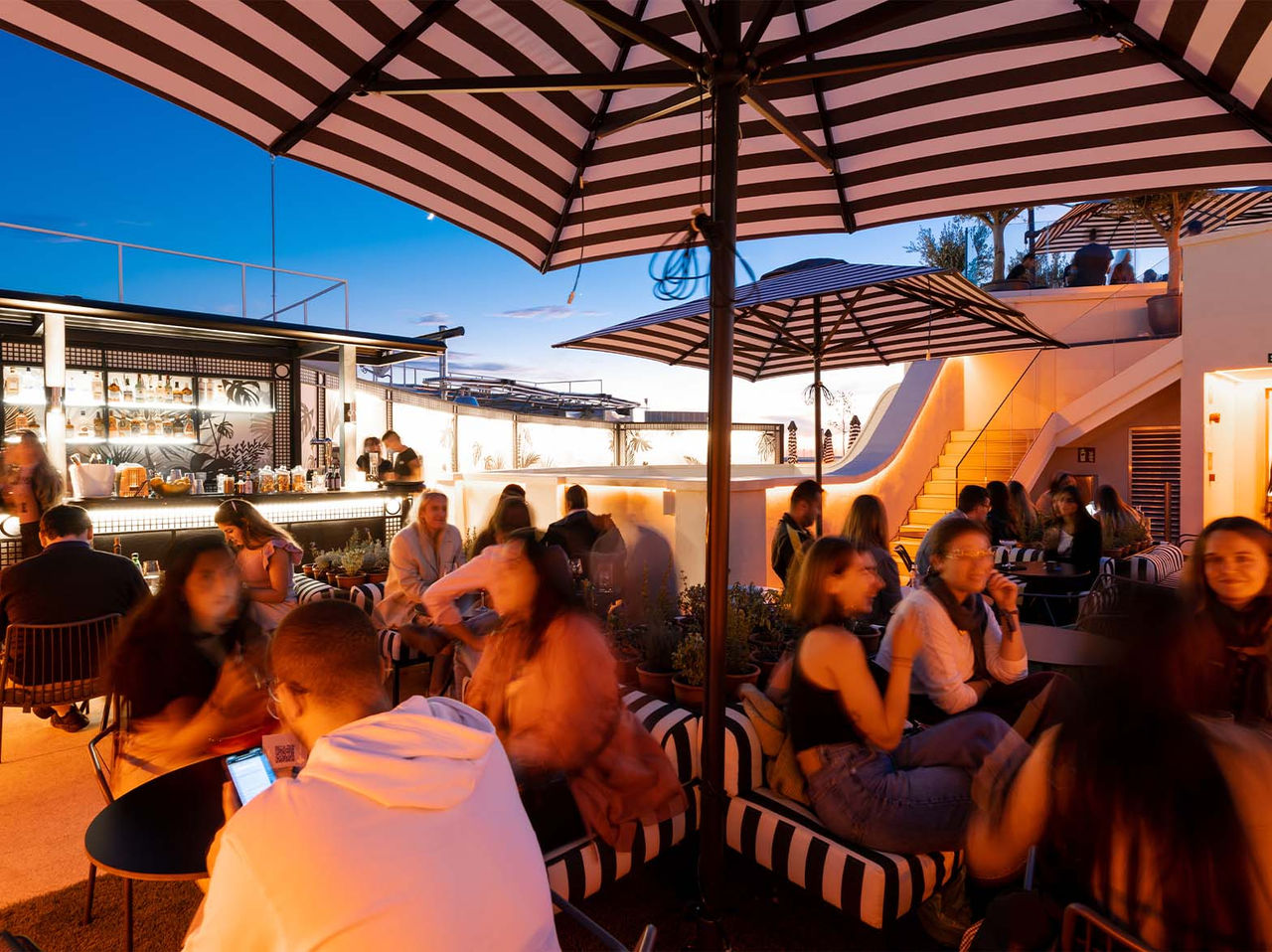 The Rooftop Bar at the Hotel in Madrid, has a large space with umbrellas, tables, and sofas
