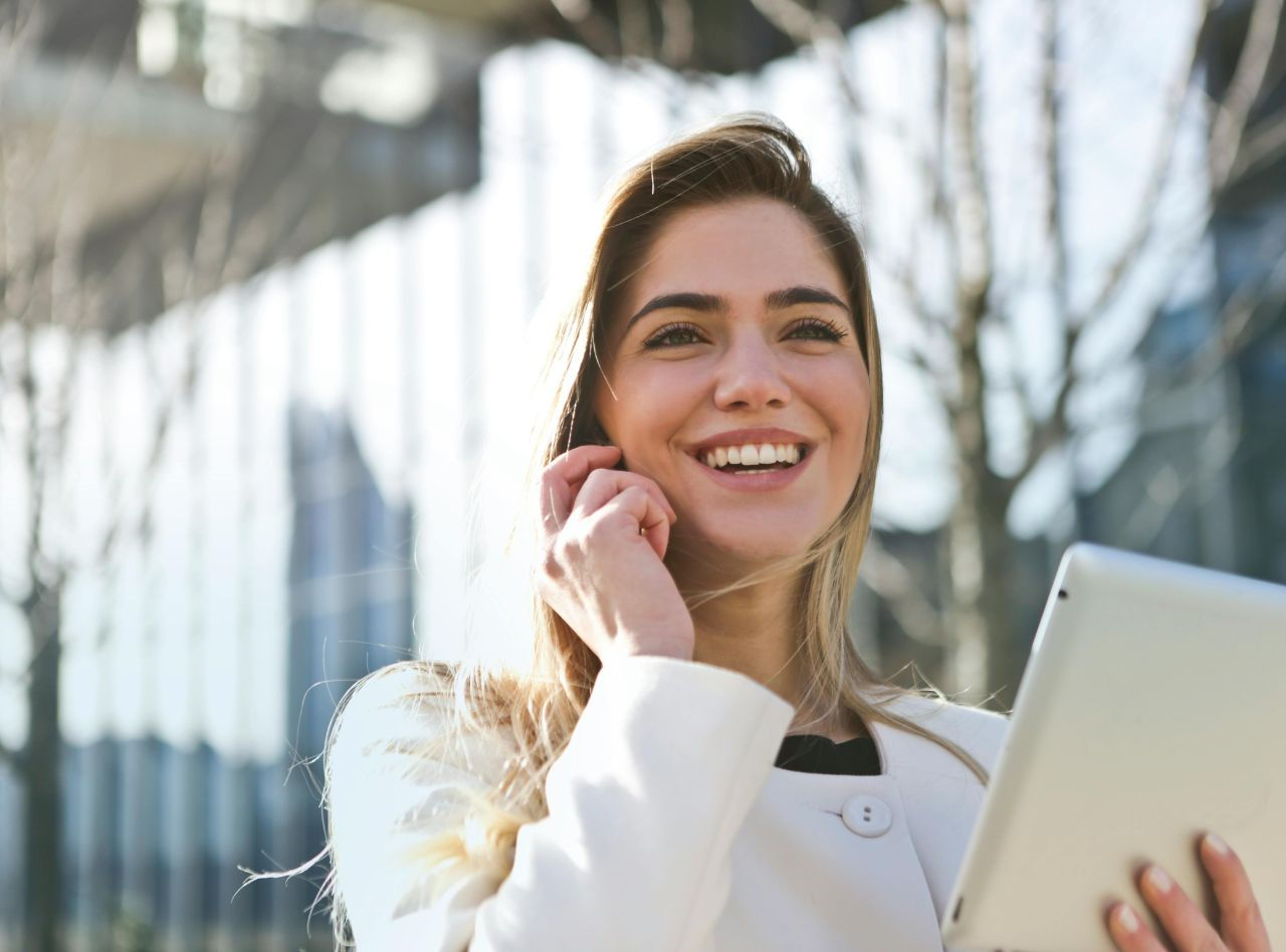 Smiling lady answers a call from a customer while holding a tablet in her hand
